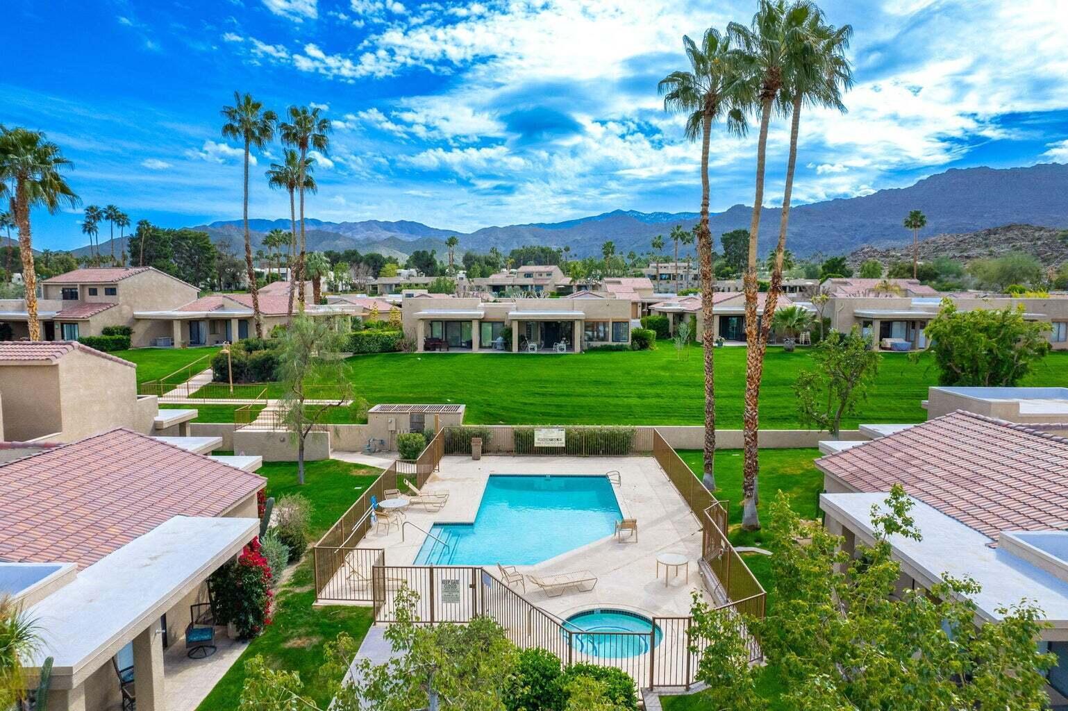One of Sommerset's pools and spas framed by lawns, palms, and red-tile-roofed homes, with the desert mountains beyond.